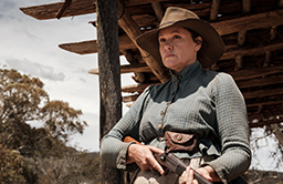 Bild på en gravid kvinna i westernkläder med ett gevär i handen
